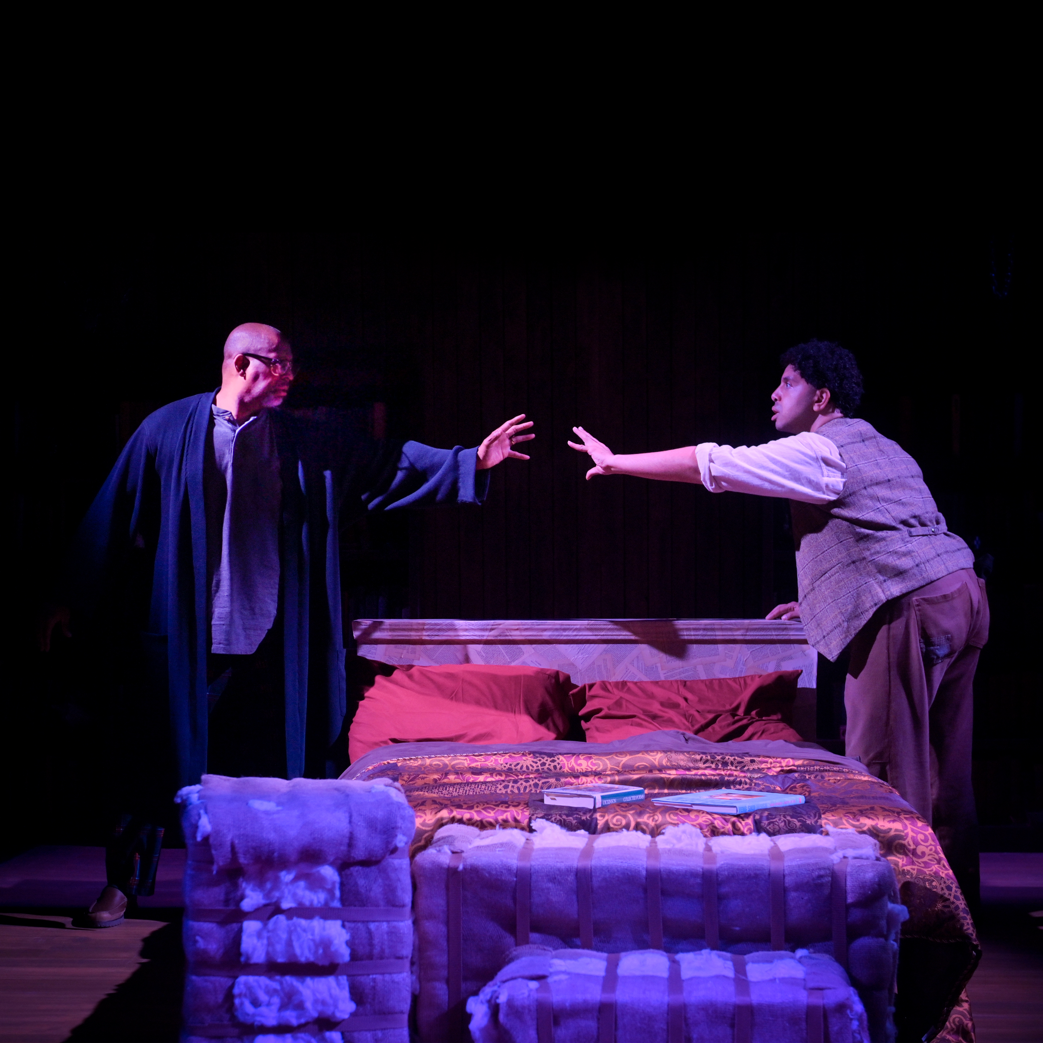 two black men reaching out to each other on either side of a double bed