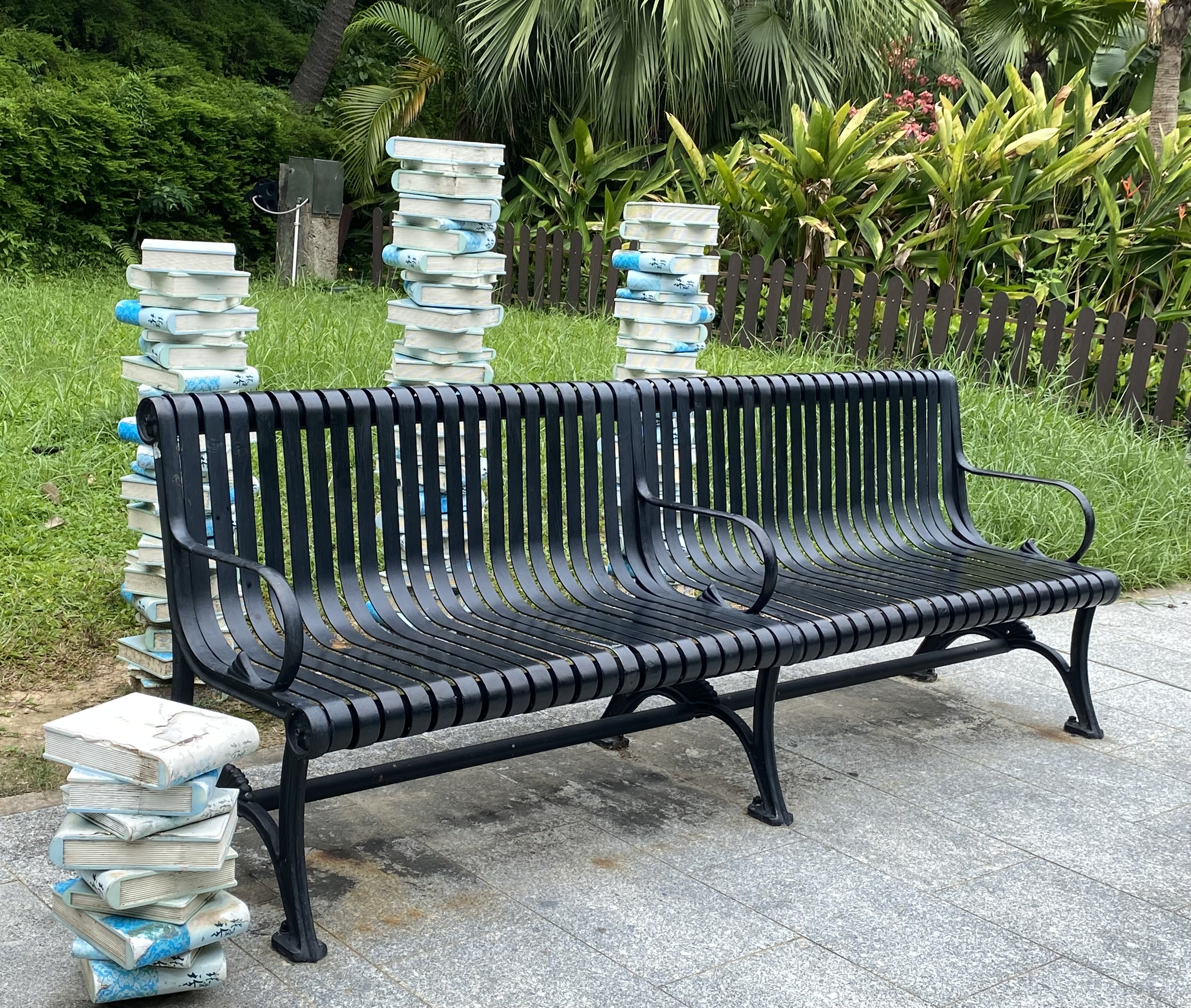 piles of books next to a park bench