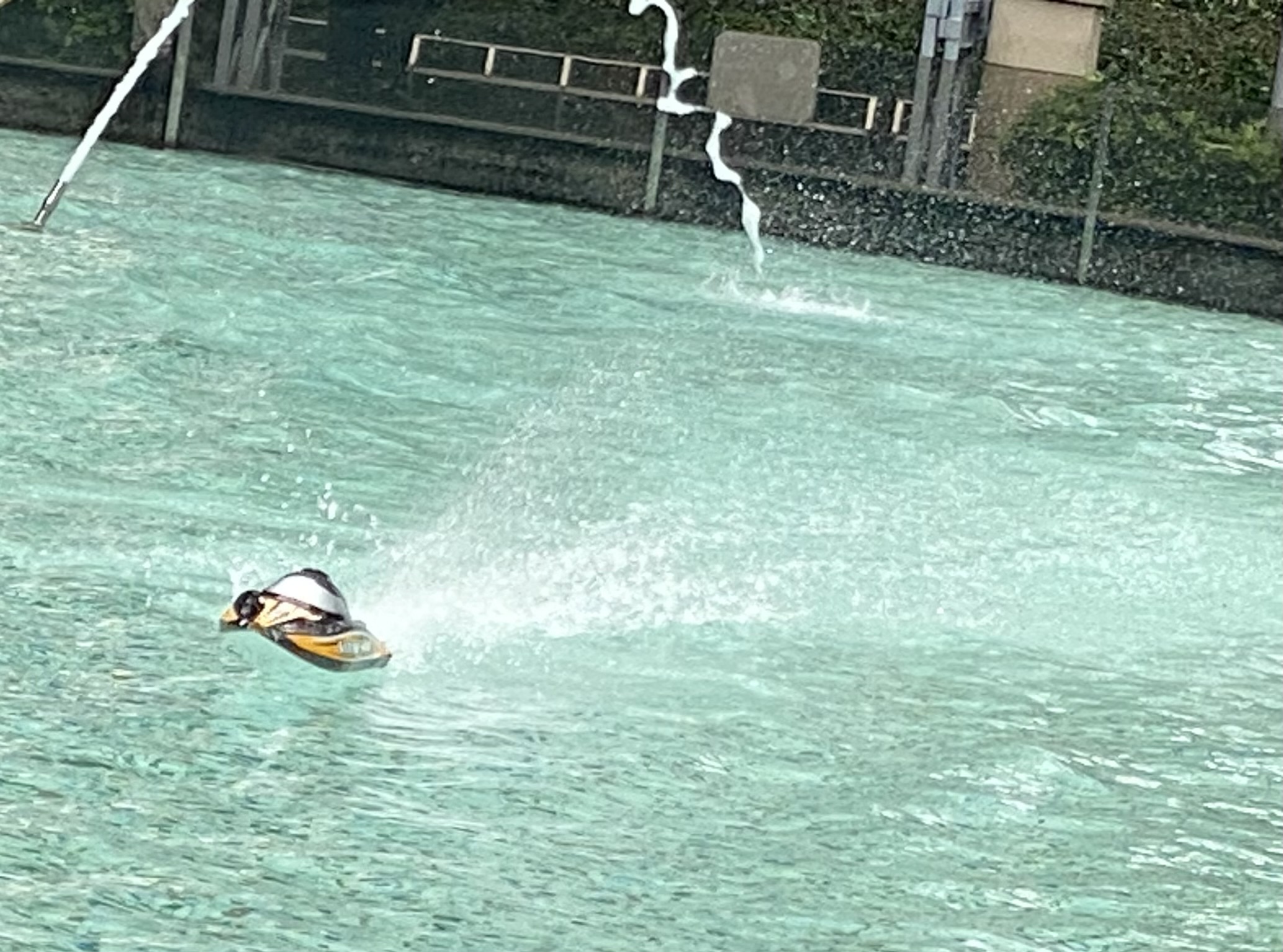 close-up of a remote control boat in a pool lined in front of a fountain