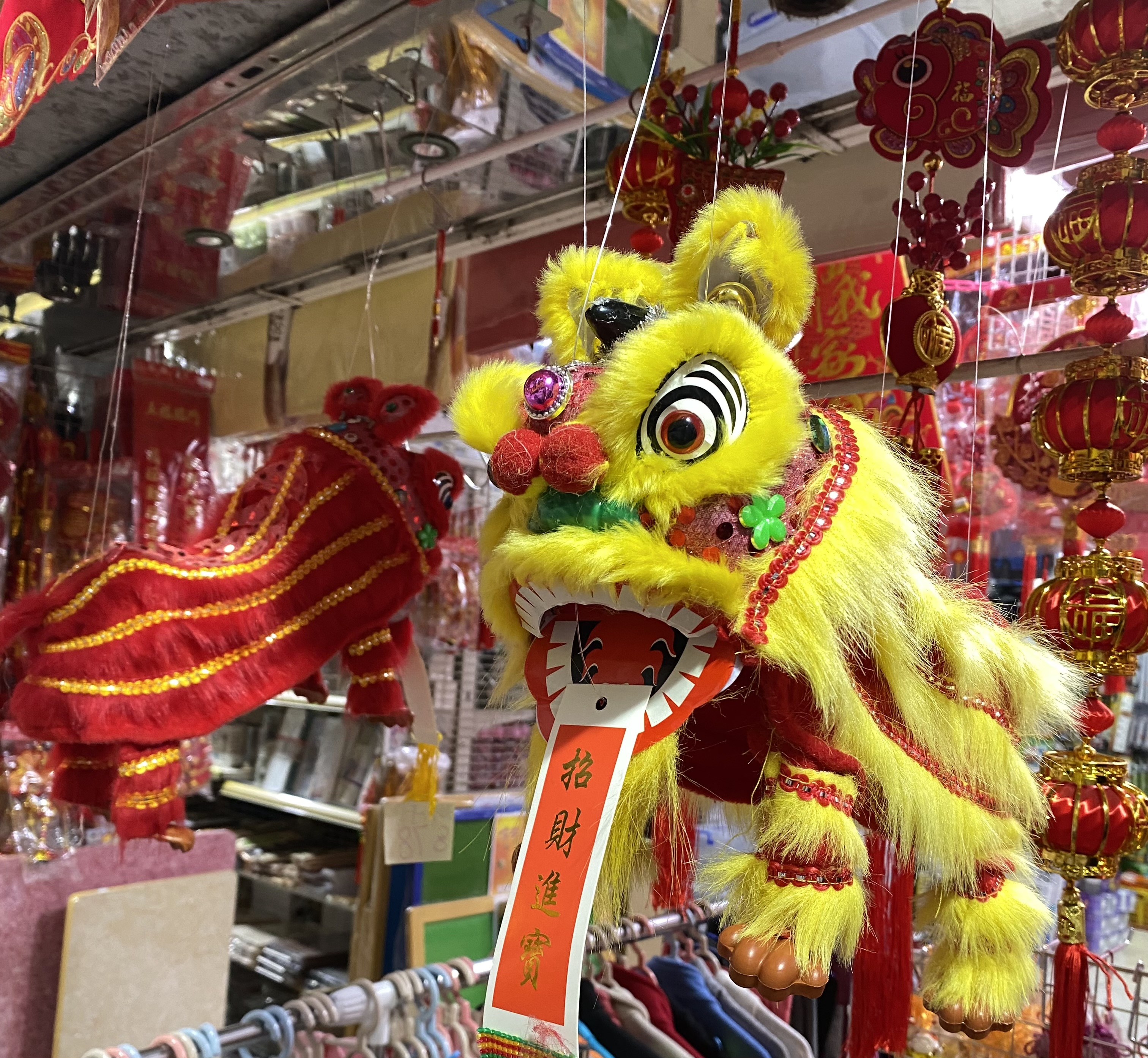 Red and lion puppets hanging outside a store.