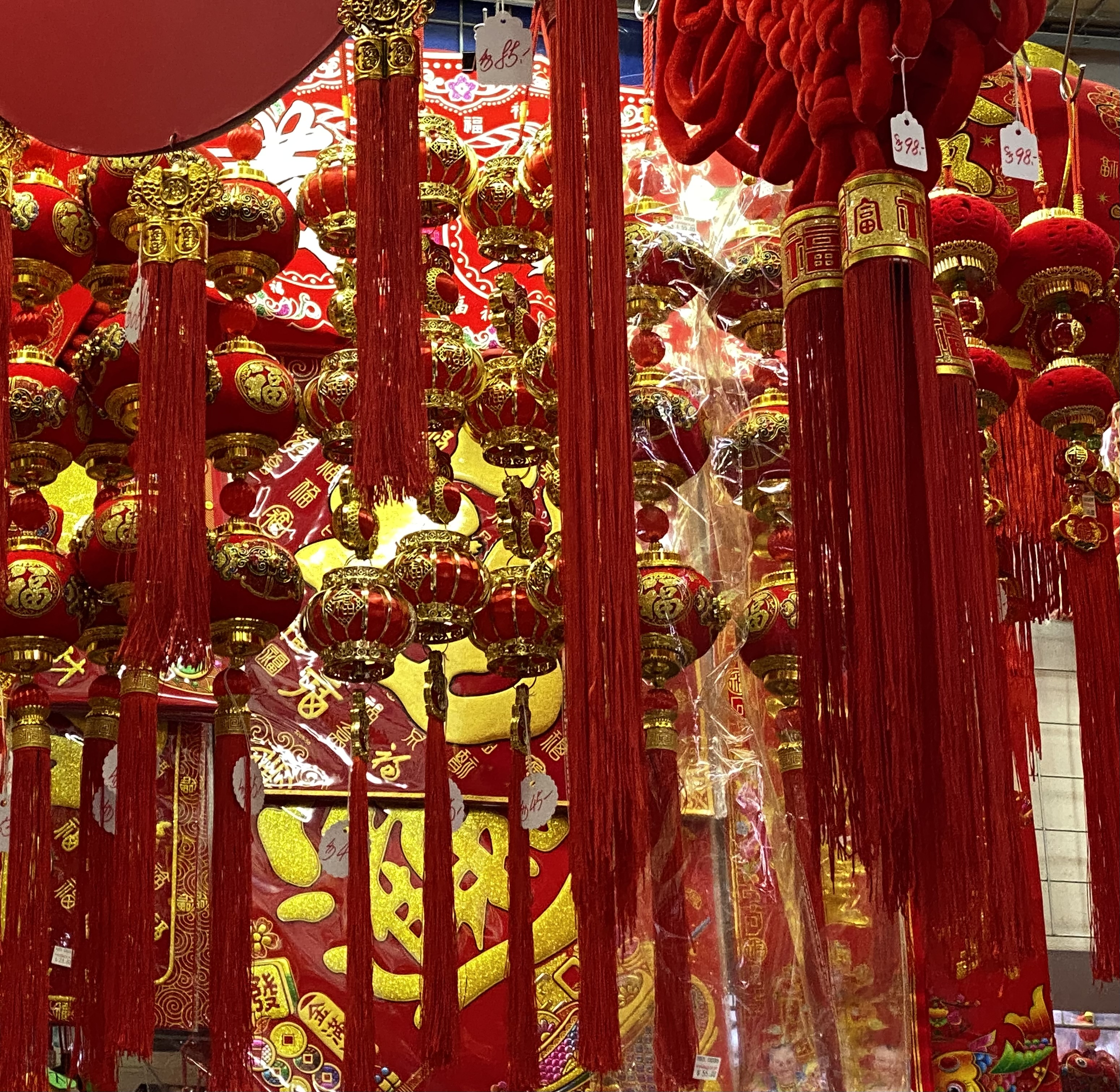 Red lanterns with tassels hanging from the ceiling of a store.