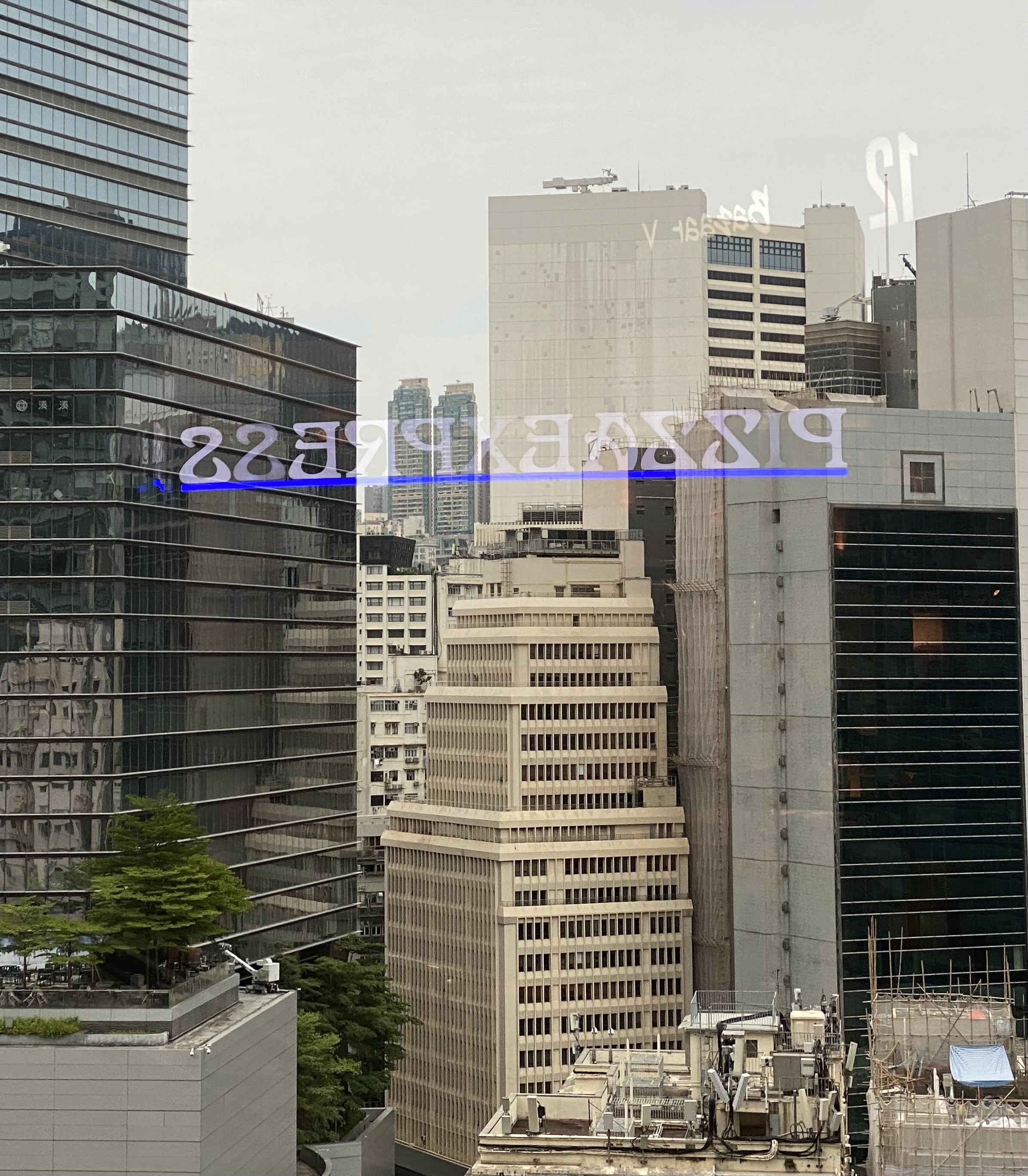 reflections of Pizza Express neon lights against tall glass pane in front of commercial buildings