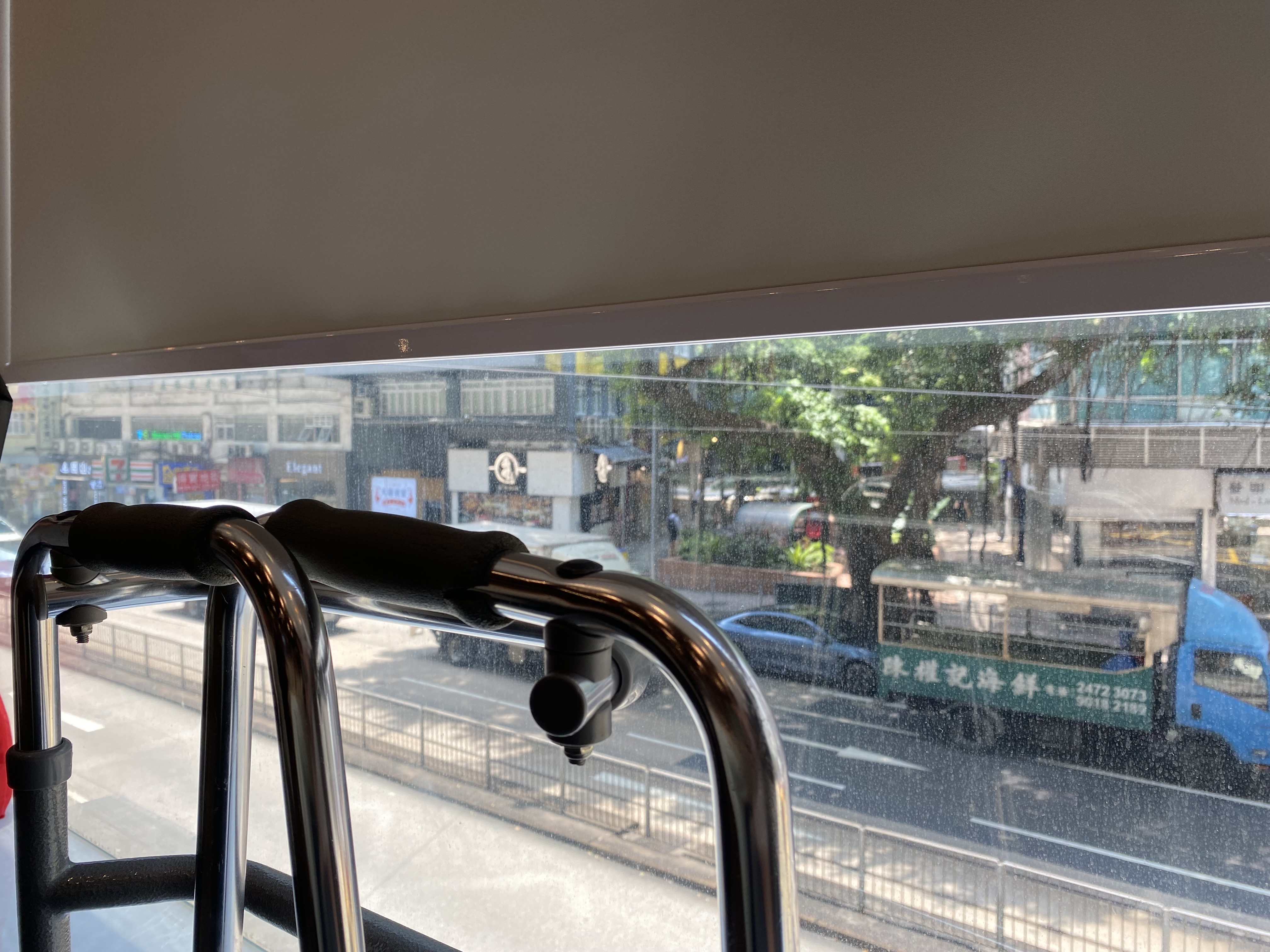 from a restaurant table, a walker leaning against the window with the blind drawn and a tree across the street, behind trucks and a car.