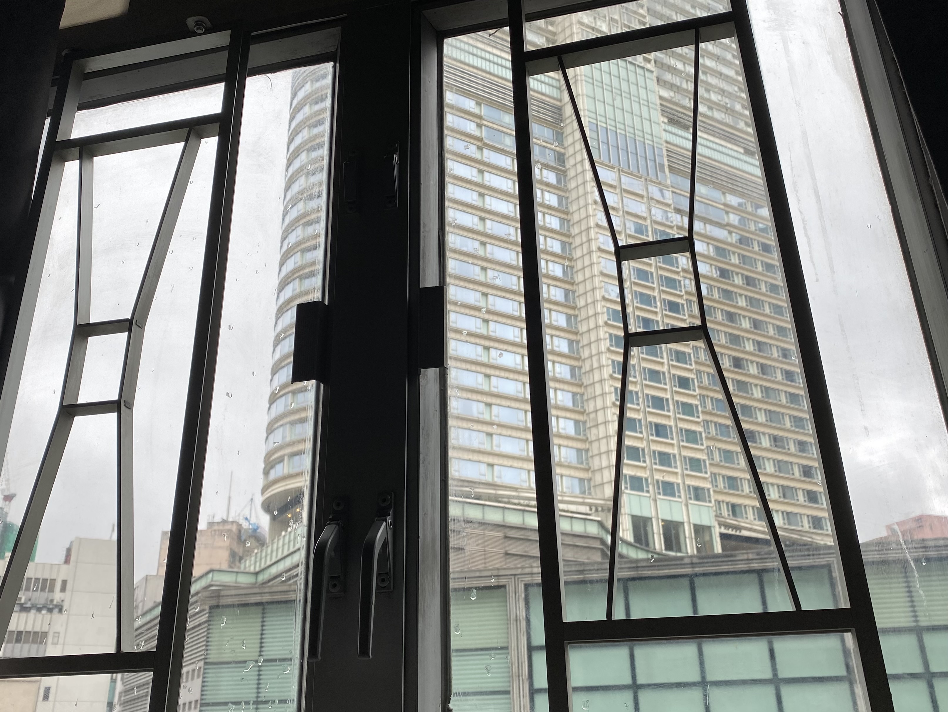 window with raindrops and a view of a tall building above a mall